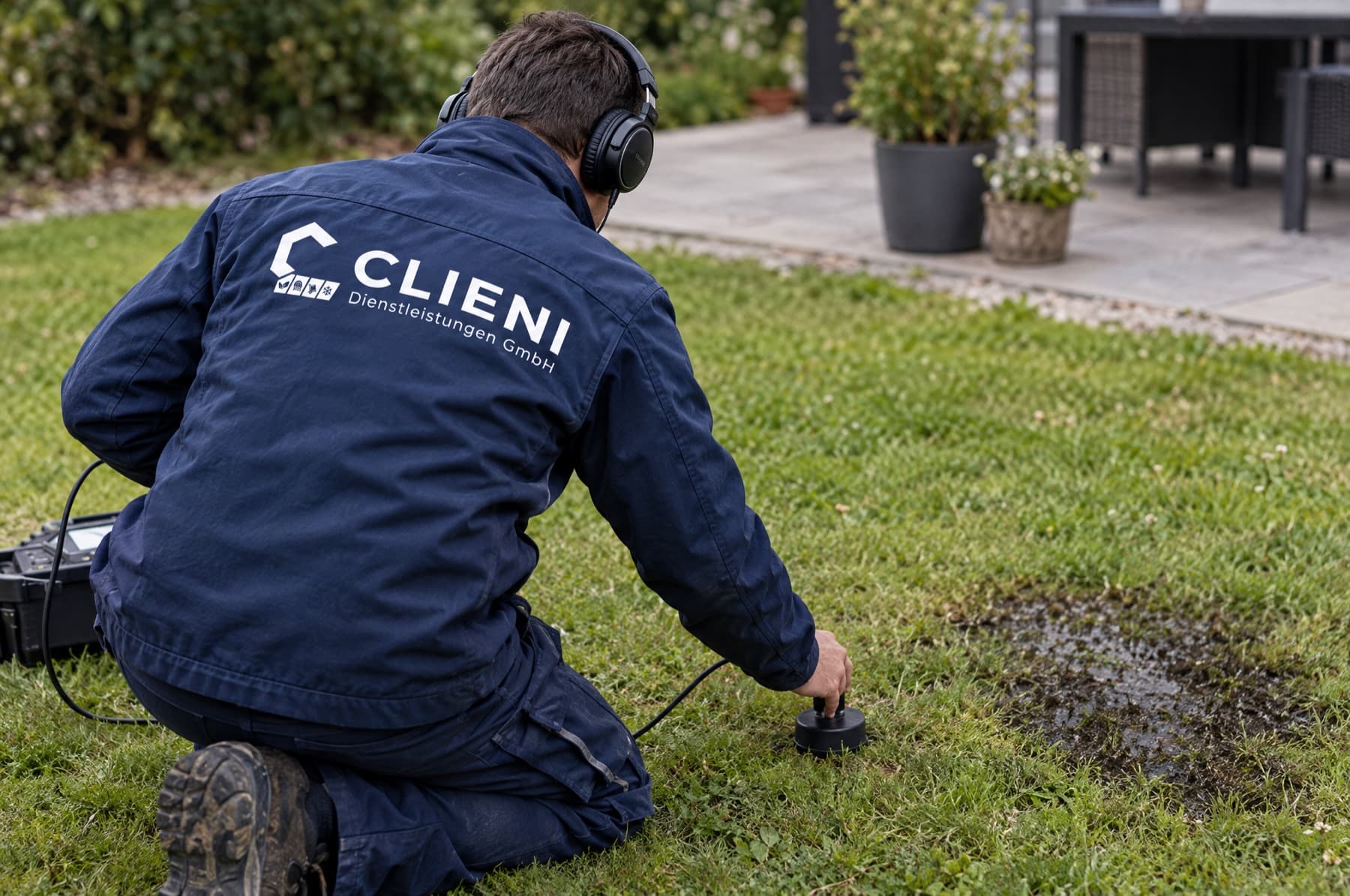 CLIENI Monteur ortet mit Bodenmikrofon einen Rohrbruch im Garten eines Einfamilienhauses